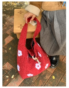 Detail of red plush tote with white floral embroidery and wooden toggle button closure