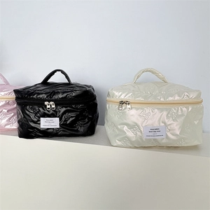 Detail of quilted PU cosmetic bags in black, beige, and pink with ribbon patterns