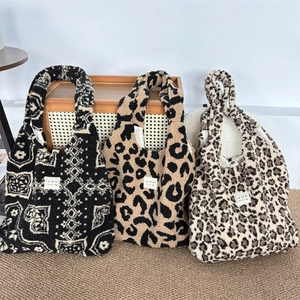 Fleece tote bags in jacquard and leopard patterns displayed on a wooden cabinet