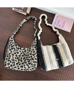 Dettaglio macro della borsa tote in peluche leopardata con texture morbida e logo metallico