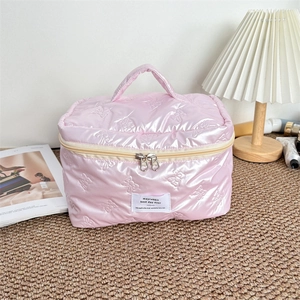 Detail of pink waterproof makeup bag featuring quilted bow pattern and dual zipper closure