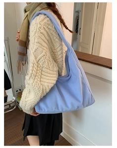 Light blue faux fur hobo bag shown on shoulder in a minimalist indoor setting