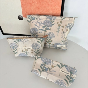 Detailed set of three floral jacquard makeup bags with zippers in various sizes