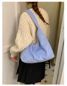 Close-up of light blue plush shoulder bag with YEYU woven label and soft texture