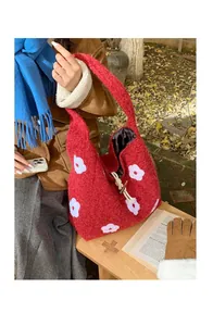 Detail of red plush knit tote bag with white floral patterns and knot closure