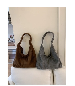 Detailed view of gray and dark brown wool tote bags placed on a minimalist white sofa