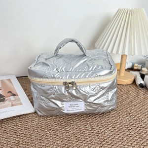 Detailed close-up of silver quilted makeup bag with metallic bunny pattern and top handle