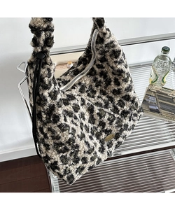 Dettaglio della borsa tote in peluche leopardata con targhetta in metallo e zip