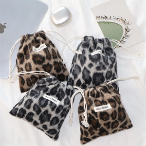 Close-up of leopard print plush drawstring pouches with soft faux fur and white woven labels