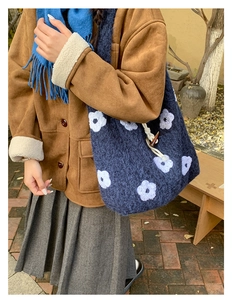 Detailed close-up of blue fuzzy tote bag with white floral embroidery and wood button