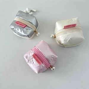 Close-up of three metallic bow-accented PU earphone cases in silver, beige, and pink