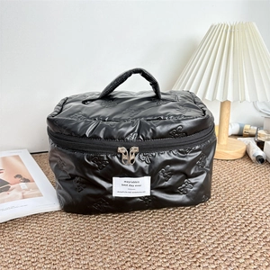 Close-up of black quilted makeup bag with embossed bunny patterns and double zippers