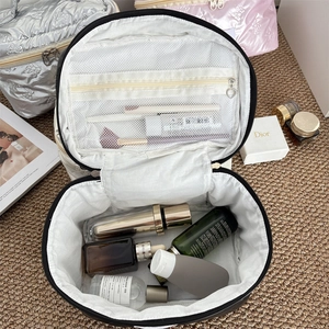 Detail of the large round makeup bag interior with mesh pocket and heart zipper