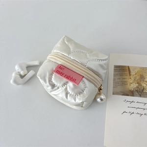 Detail of white quilted heart-stitched earphone pouch with a decorative pearl zipper pull