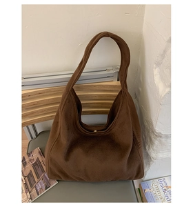 Detail of dark brown suede tote bag featuring a wide shoulder strap and gold magnetic snap