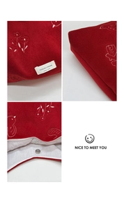 Detail of red velvet tote bag showing white bird embroidery and magnetic snap closure