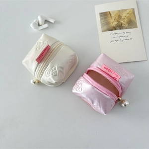 Close-up of quilted PU earphone pouches with bow embroidery and pearl zipper charms