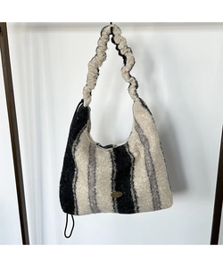 Dettaglio della borsa hobo in peluche a righe con manico arricciato e targhetta in metallo