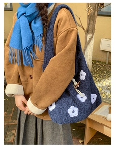 Detail of navy plush tote bag featuring white floral embroidery and horn buckle closure