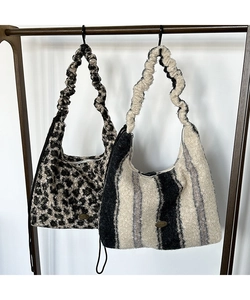 Dettaglio di borse tote in peluche leopardate e zebrate con manici scrunchie e logo