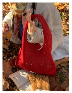 Detail of red fabric tote bag with white bird embroidery and autumn outdoor vibe