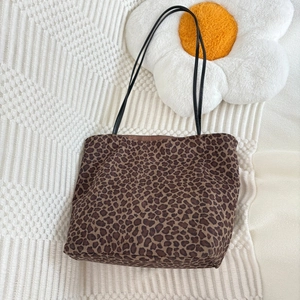 Detailed view of leopard print faux suede tote bag on a textured white knit background