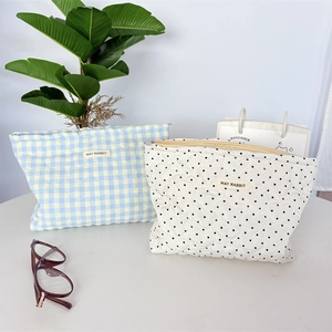 Quilted cotton cosmetic bags in checkered and polka dot styles on a minimalist white desk