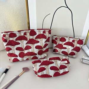 Détail de trois trousses de maquillage en toile jacquard à motifs de champignons rouges