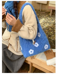 Close-up of blue fuzzy plush tote bag with white floral embroidery and wooden button detail