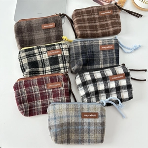 Flat lay of retro plaid canvas coin purses and cosmetic bags in various colors on a white desk