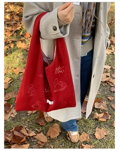 Detailed white forest embroidery on red velvet tote bag showing bird and house patterns