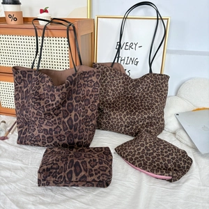 Detail view of leopard print suede tote bag set with matching zip pouches on a desk