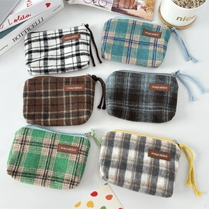 Flat lay of retro plaid canvas coin purses with leather logo and woven rope zipper pull