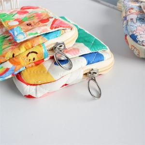 Close-up of quilted floral fabric texture with cartoon print and metal ring zipper pull