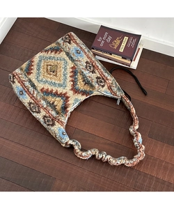 Dettaglio dei motivi jacquard geometrici e della tracolla a balze della borsa