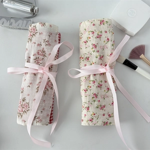 Detail of floral fabric makeup brush rolls with elegant pink ribbons and rose patterns