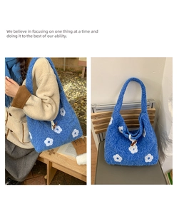 Detail of blue plush tote bag featuring white floral embroidery and horn button closure