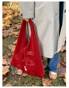 Close-up of bird and house embroidery on a red velvet tote bag for autumn