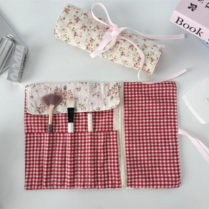 Floral fabric makeup brush roll with red gingham pattern and pink ribbon closure detail