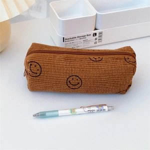 Nahaufnahme der karamellbraunen Cord-Federmappe mit schwarz gesticktem Smiley-Motiv-Detail