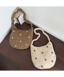 Nahaufnahme von Plüsch-Schultertaschen mit 3D-Blumen auf einem Holzboden