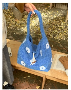 Detail of blue plush tote bag featuring floral embroidery and a wooden toggle closure