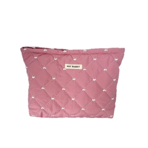 Pink quilted makeup bag with heart embroidery and central brand logo on white background
