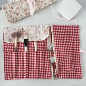 Floral lining and red gingham makeup brush roll with multiple slots and heart zipper