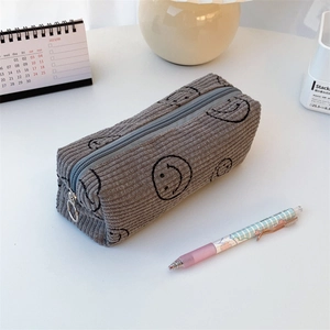 Detailaufnahme der grauen Cord-Federtasche mit bestickten lächelnden Gesichtern-Mustern