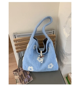 Detail of blue plush tote bag featuring white floral embroidery and wooden toggle closure