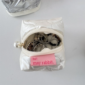 Close-up of quilted PU mini storage bag featuring pearl zipper and internal jewelry storage