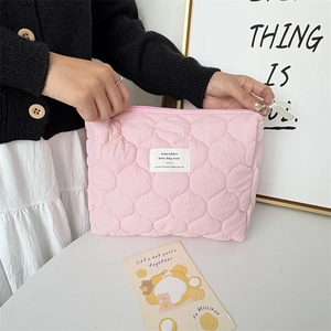 Detail showing pink quilted cosmetic bag with ribbon zipper and woven label