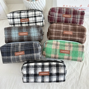 Detail view of multicolored plaid wool pencil cases with metal zipper and leather label