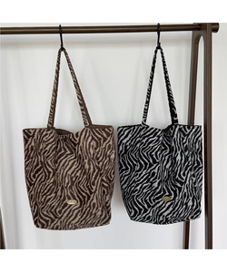 Detailed texture of zebra print fabric tote bags with a golden metal logo plate